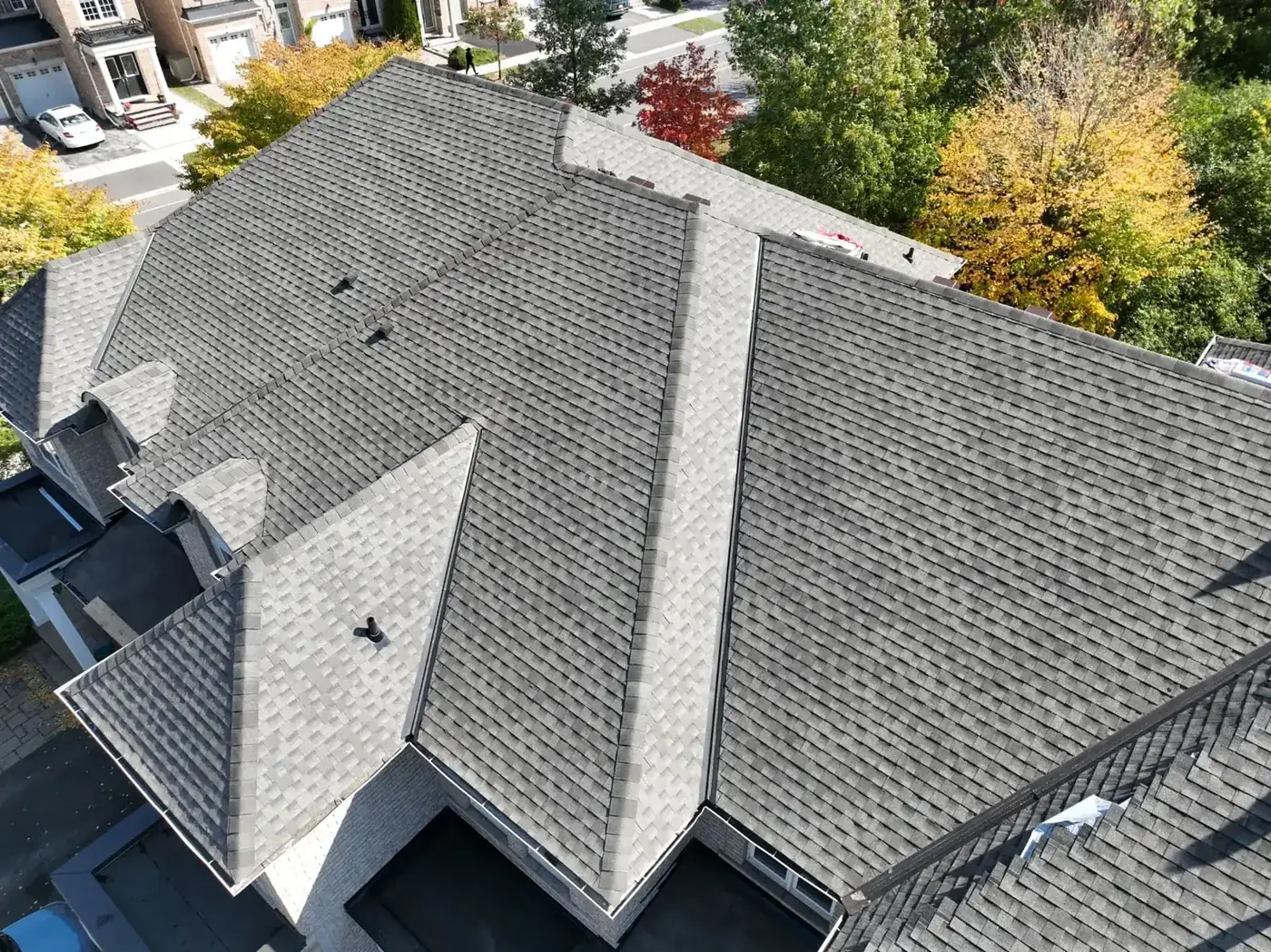 Overhead drone view of a completed Oakville shingle roof with crisp ridge caps, hips and valleys on a two-storey brick home