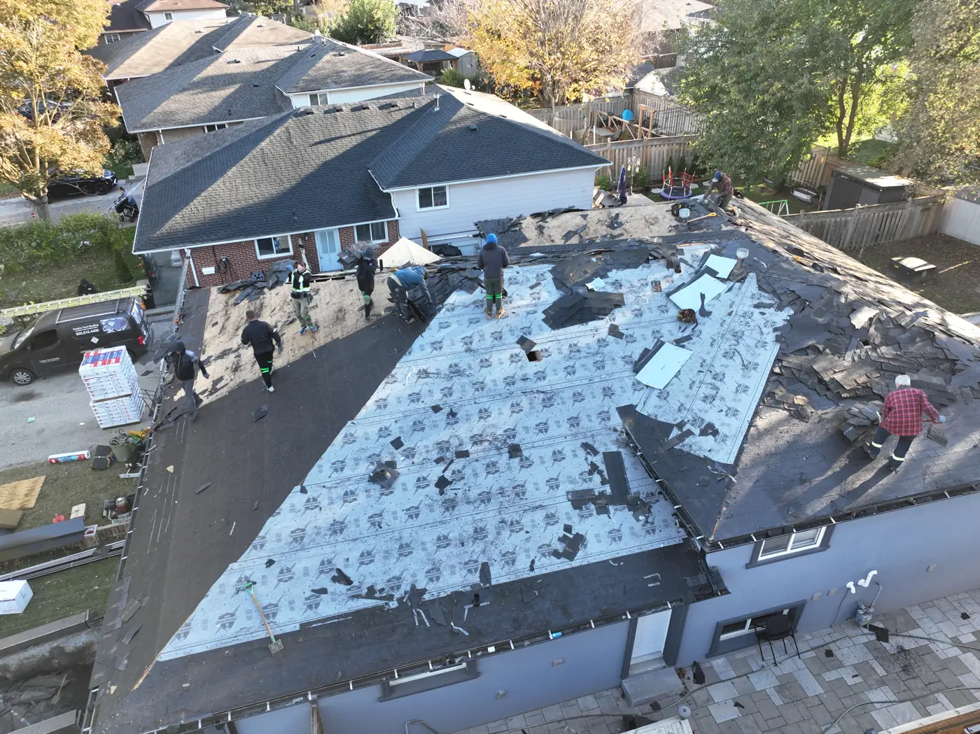 Wider view of a Hamilton roof tear-off and cleanup with new shingle bundles staged on the roof