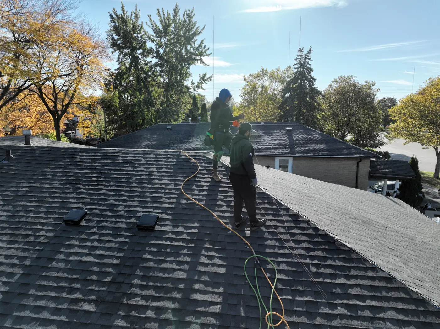 Nearly finished Hamilton hip roof with two roofers working along the ridge
