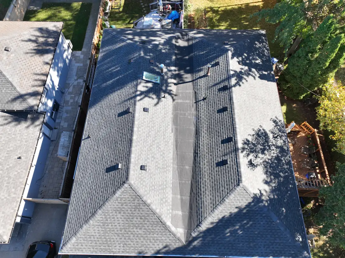 Top-down drone view of the new shingle roof on the Bonnymede Drive home, showing the skylight, vents and flat centre section